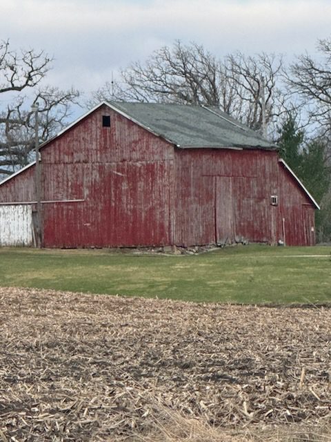Weathered red barn by harvested field