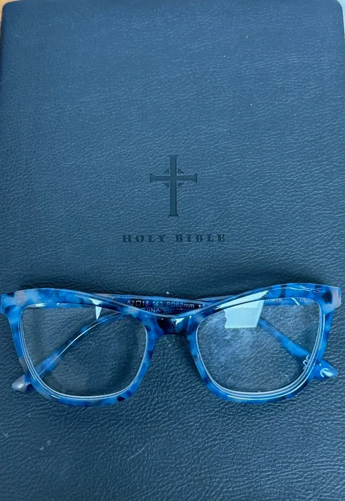 Blue eyeglasses on black Holy Bible cover