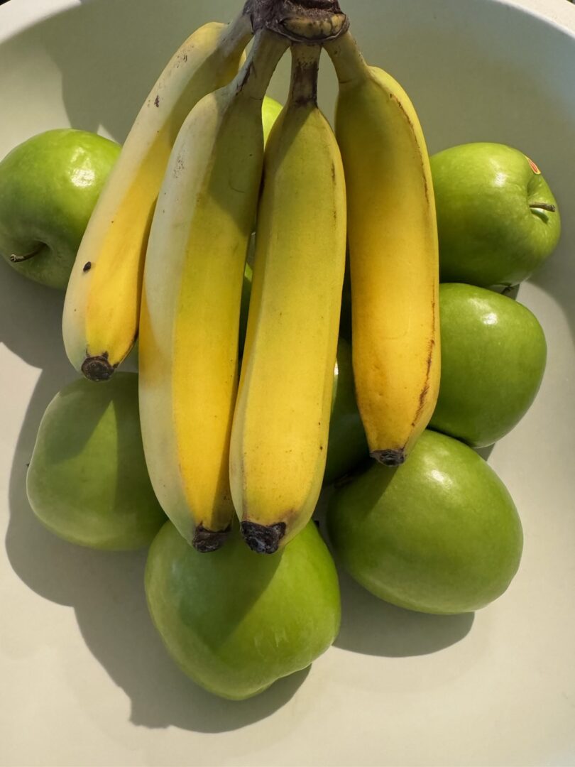 Bowl of green apples topped with bananas