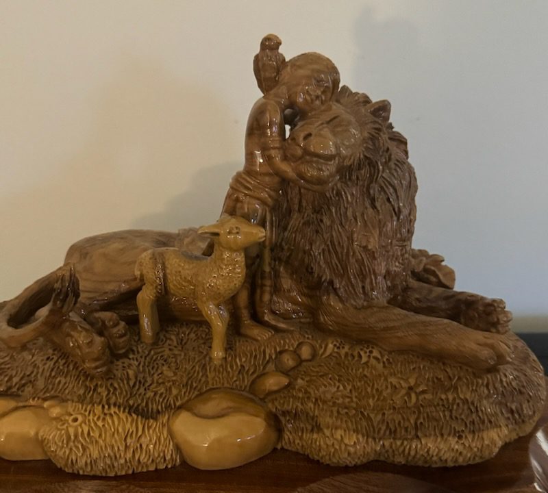 Wooden carving of person hugging lion and lamb