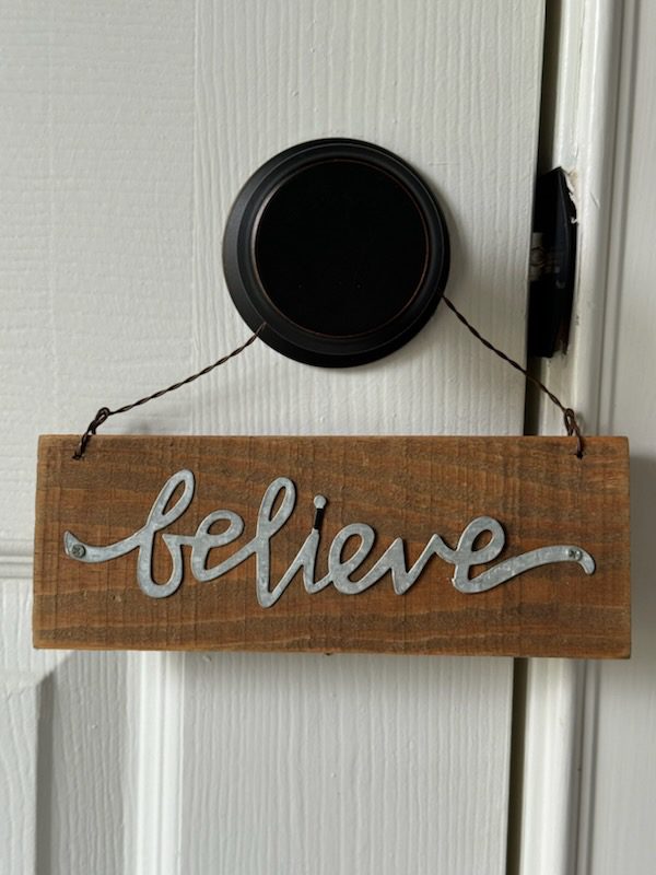 Rustic wooden "believe" sign hanging on doorknob